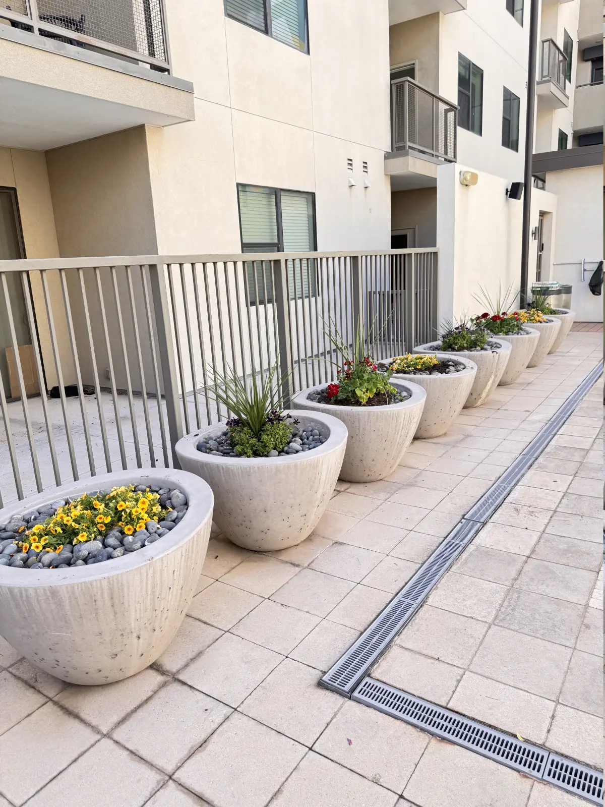 Decorative planter line and clean paving edges in a residential complex courtyard.