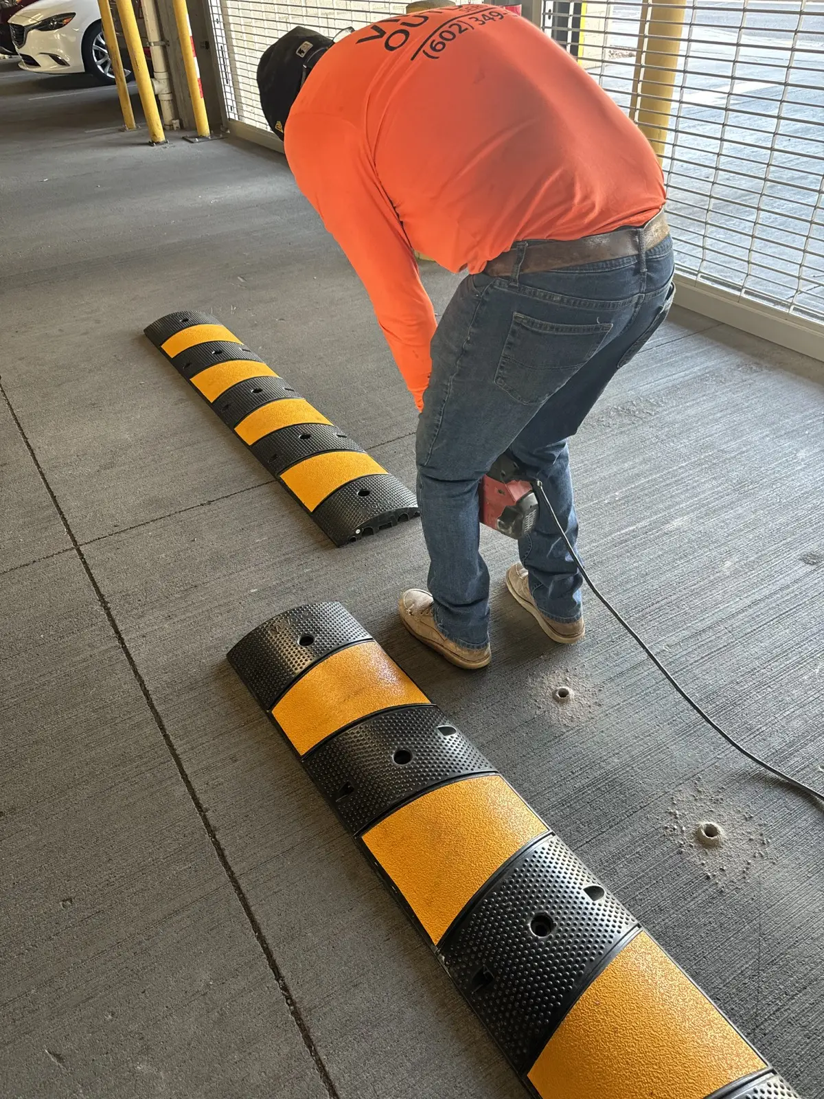 Technician installing traffic calming hardware in a garage drive lane.